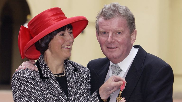 BBC sports commentator John Motson with his wife Anne poses for photographs after receiving an OBE from Queen Elizabeth II at Buckingham Palace in 2001
