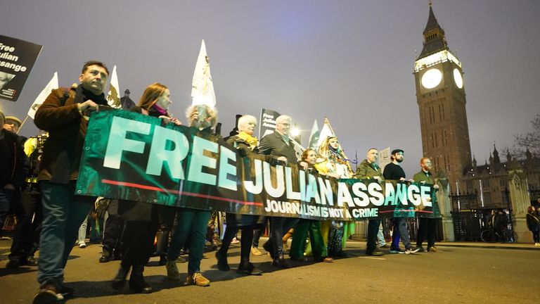 Campaigners  walk past Big Ben holding a huge banner demanding Julian Assange is freed 