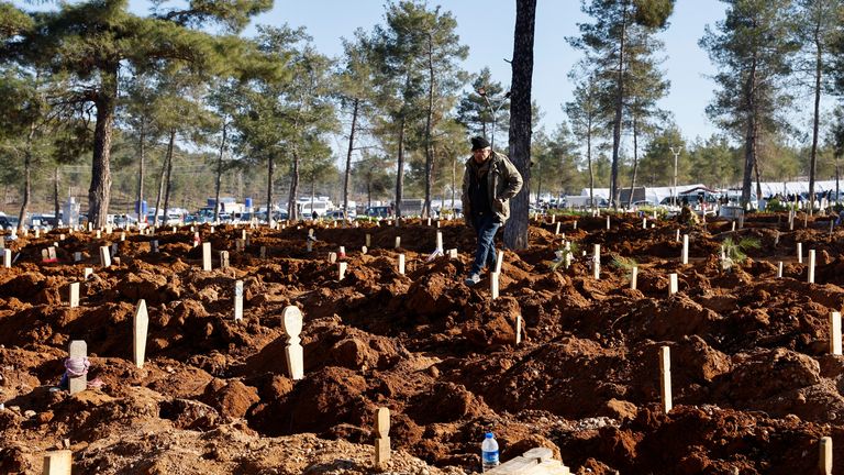 A man stands amongst graves in a cemetery where victims of the deadly earthquake are buried, in Kahramanmaras, Turkey 