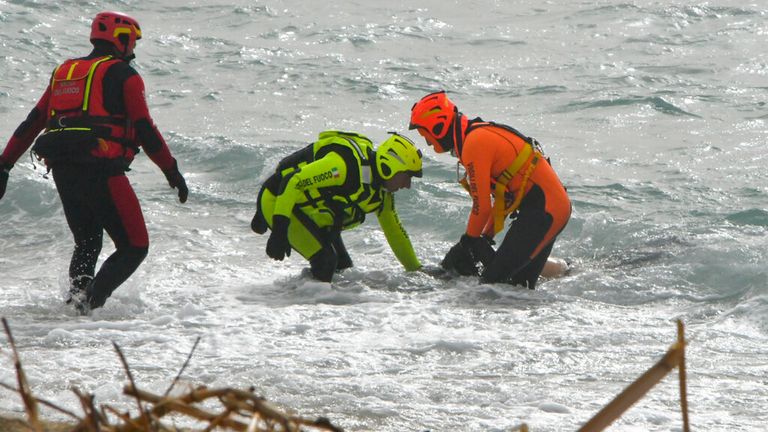 Rescuers recover a body after a migrant boat broke apart in rough seas