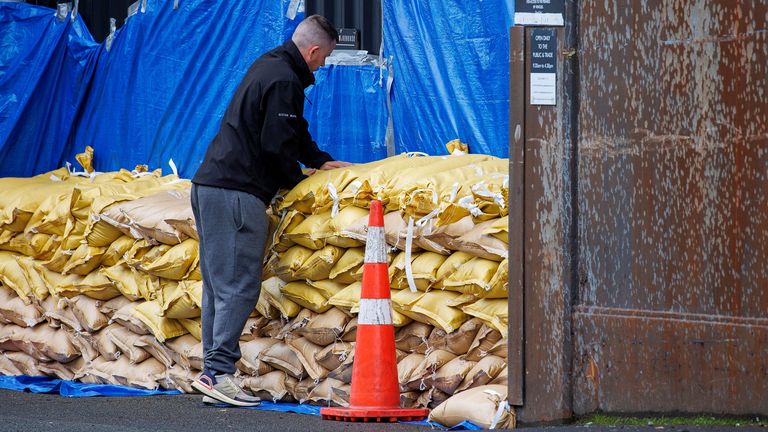 A man stacks up sandbags to protect a warehouse before the arrival of Cyclone Gabriele in Auckland, New Zealand, February 12, 2023. AAP Image/David Rowland via REUTERS ATTENTION EDITORS - THIS IMAGE WAS PROVIDED BY A THIRD PARTY. NO RESALES. NO ARCHIVE. AUSTRALIA OUT. NEW ZEALAND OUT