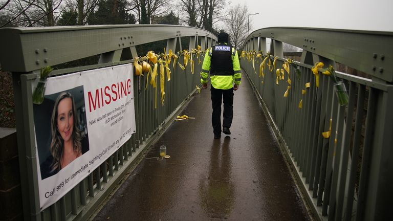 A police officer walks past a missing person appeal poster for Nicola Bulley and yellow ribbons and messages of hope tied to a bridge over the River Wyre in St Michael&#39;s on Wyre, Lancashire, as police continue their search for Ms Bulley, 45, who vanished on January 27 while walking her springer spaniel Willow shortly after dropping her daughters, aged six and nine, at school. Picture date: Thursday February 16, 2023.