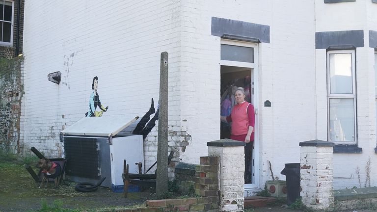 Property tenant, Polla Maria Oberscziam, stands in the doorway of her home where a new artwork by street artist Banksy, titled &#39;Valentine&#39;s Day Mascara&#39; has been painted on the side of a building in Margate, Kent