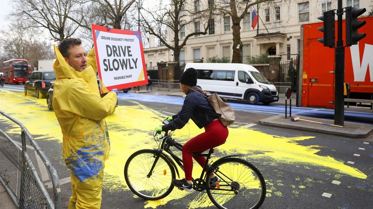 A member of protest group &#39;Led by Donkeys&#39; holds a sign, as paint in the colours of the Ukrainian flag is spread on a road, ahead of the first anniversary of Russia&#39;s invasion of Ukraine, outside the Russian Embassy in London, Britain February 23, 2023. REUTERS/Hannah McKay
