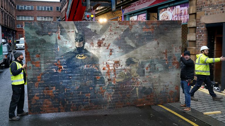 A mural of Batman and Robin is moved into position by set dressers as they prepare the set for what is believed to be the film set of the new Batgirl movie on Parnie Street in Glasgow. Road closed barriers and traffic cones have been erected on Parnie Street and King Street, to the east of the city centre, as preparation work gets underway for filming: Monday January 10, 2022.