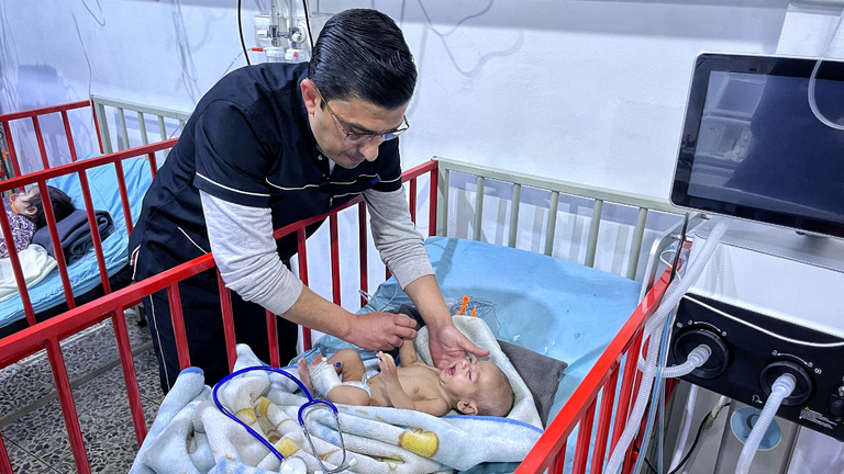 A doctor checks on a baby at Sham hospital