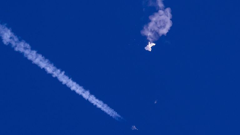 The remains of a large balloon float over the Atlantic Ocean, just off the coast of South Carolina, with a fighter jet and its wake below in this photo provided by Chad Fish, Saturday, Feb. 22.  February 4, 2023. The downing of a suspected Chinese spy balloon by a missile from an F-22 fighter jet caused a stir over a tourist hub in the state, drawing crowd reactions ranging from bewildered stares to pain and cheers. (via The Associated Press Chad fish)
