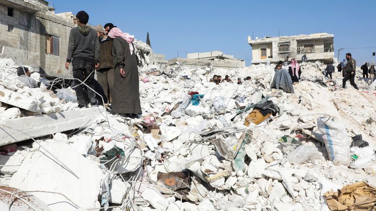 People stand on the rubble of damaged buildings in the aftermath of an earthquake, in rebel-held town of Harem, Syria February 13, 2023. REUTERS/Mahmoud Hassano
