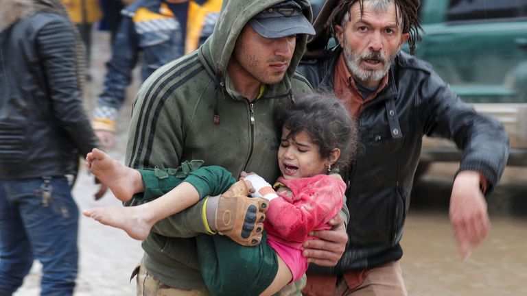A man carries a girl following an earthquake, in rebel-held town of Jandaris, Syria 