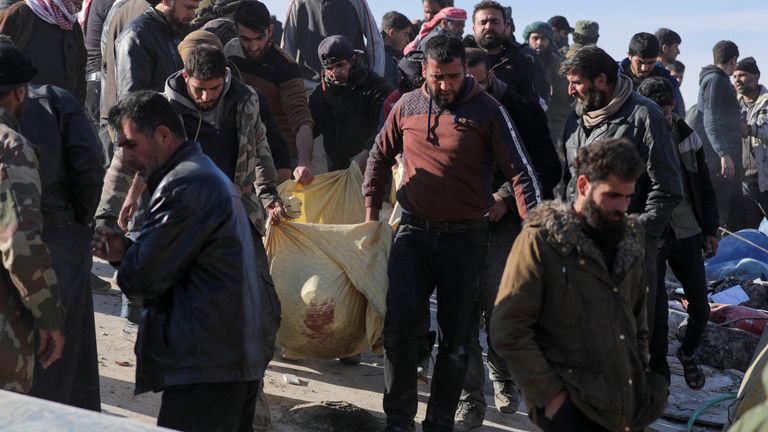 People carry a victim out of the rubble in the aftermath of an earthquake, in rebel-held town of Jandaris, Syria
