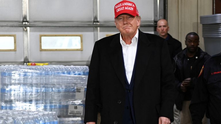 Former US President Donald Trump walks past stacks of donated water bottles, holding "trump card" A tag on a train carrying hazardous waste was recently derailed during an event at a firehouse in East Palestine, Ohio, U.S., February 22, 2023.REUTERS/Alan Freed