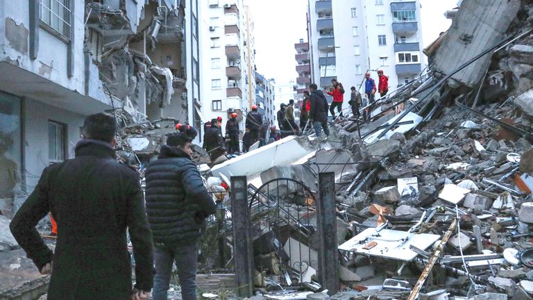 People and rescue teams try to reach trapped residents inside collapsed buildings in Adana, Turkey, 
Pic:AP
