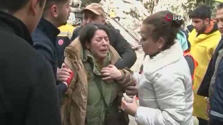 A woman is comforted on the ground after being rescued from a building in Adana in Turkey