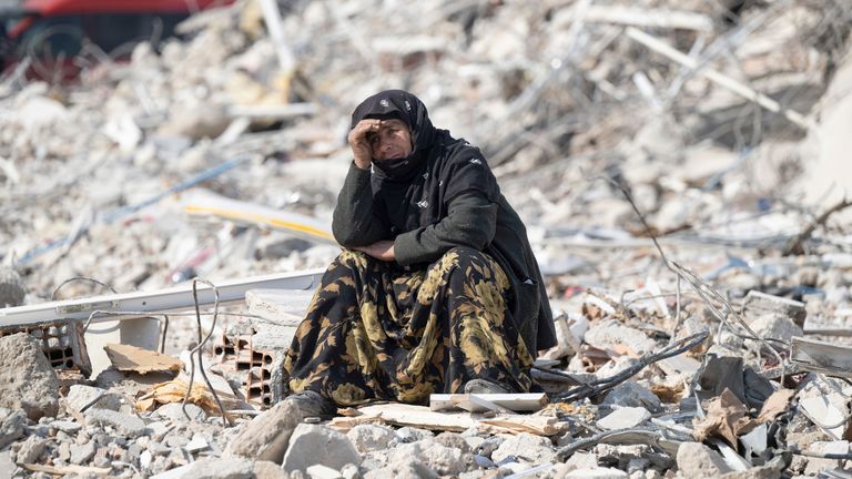 11 February 2023, Turkey, Antakya: A woman sits among the rubble and watches the recovery of victims. Thousands of victims are still believed to be trapped under the rubble. Teams of helpers from all over the world are working in the disaster area. Photo by: Boris Roessler/picture-alliance/dpa/AP Images