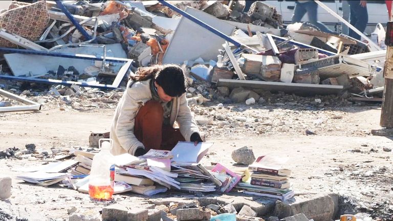 A woman search through scraps in ruined Adiyaman, Turkey