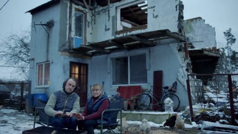 A couple sitting outside what remains of their home 