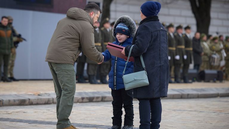 Ukrainian President Volodymyr Zelenskyy, left, gives the award of Hero of Ukraine to relatives of a killed soldier during a commemorative event on the occasion of the Russia Ukraine war one year anniversary, in Kyiv, Ukraine, Friday, Feb. 24, 2023. (Ukrainian Presidential Press Office via AP)