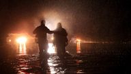 Sonoma County Fire&#39;s Eric Gromala guides a woman to safety after her vehicle stalled out in deep floodwater on Eastside Road just south of Riverfront Regional Park near Forestville, Calif., late Thursday, March 9, 2023. (Kent Porter/The Press Democrat via AP)