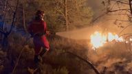 Firefighter hoses a blaze in a forest in Spain