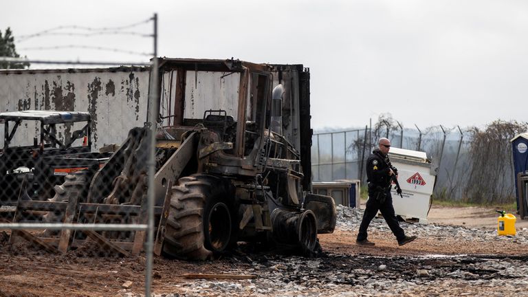 An Atlanta police officer walks by a burnt tractor at the site of the proposed Atlanta Public Safety Training facility following vandalism by protestors in Atlanta, Georgia, U.S., March 6, 2023. REUTERS/Alyssa Pointer
