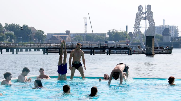 People swim in a floating swimming pool anchored on the bank of Spree river in Berlin, Germany