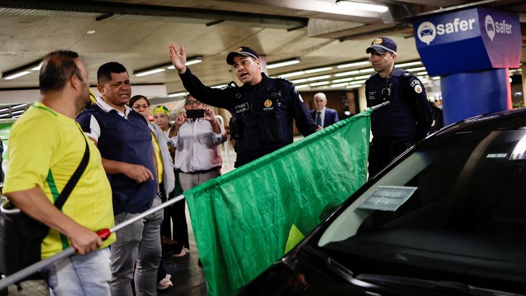 Police members chat with Bolsonaro supporters while tightening airport security