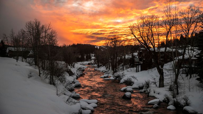 Water flows down the Truckee River lined with snow on the riverbanks during sunset in Truckee, Calif. on Friday, March 10, 2023. (Stephen Lam/San Francisco Chronicle via AP)