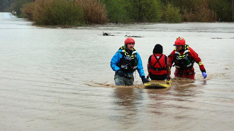 State Parks water technicians Jeremy Paiss and Bryan Kine carry Lizbeth Hernandez to safety after her truck was swept away by floodwaters along Paulsen Road in Watsonville, Calif., on Friday, March 10, 2023. Hernandez, who cannot swim, si lay on the roof of her truck for more than an hour until Paiss and Kine were able to reach her and get her to safety.  (Shmuel Thaler/Santa Cruz Watchman via AP)