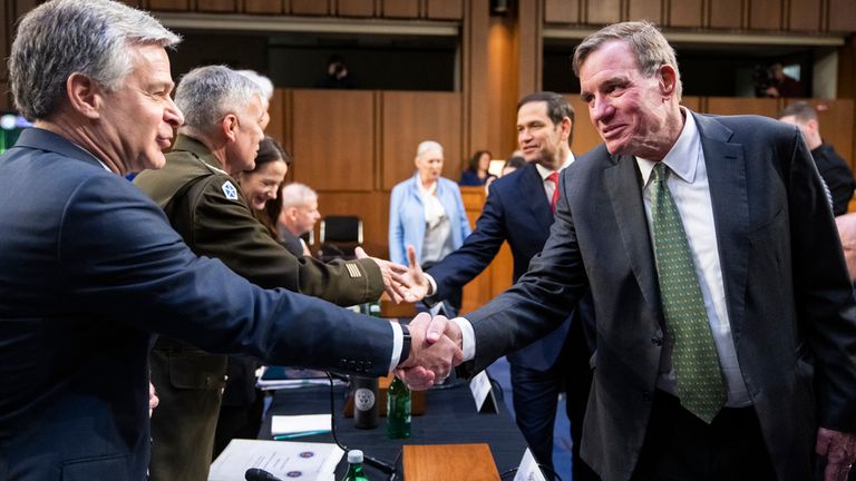 FBI Director Christopher Frey (left) shakes hands with Chairman Mark Warner during a committee hearing