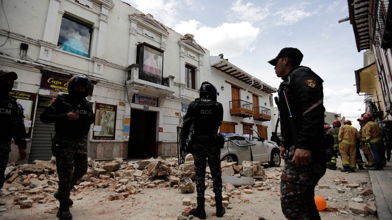 Police stand around a building damaged after an earthquake struck Cuenca