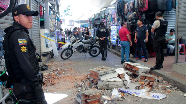 Police stand near fallen debris from a building in a commercial area after an earthquake rocked Machala, Ecuador