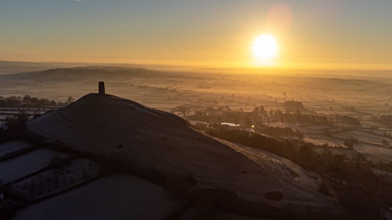 The sun rises over the Somerset Levels and strikes fields around Glastonbury Tor