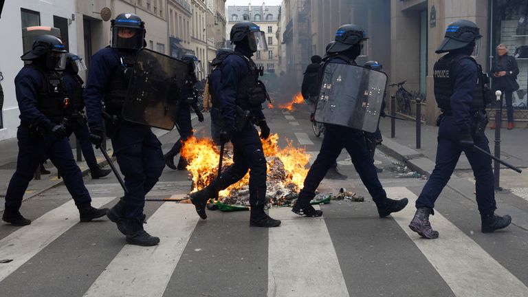 French riot police walk past burning garbage bins amid clahes with protesters during a demonstration as part of the ninth day of nationwide strikes and protests against French government&#39;s pension reform, in Paris, France, March 23, 2023. REUTERS/Gonzalo Fuentes