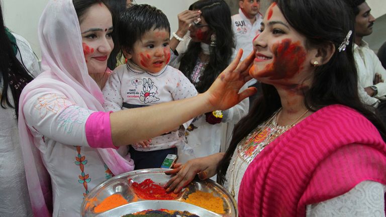 Women from the Pakistani Hindu community put colours of each others faces 