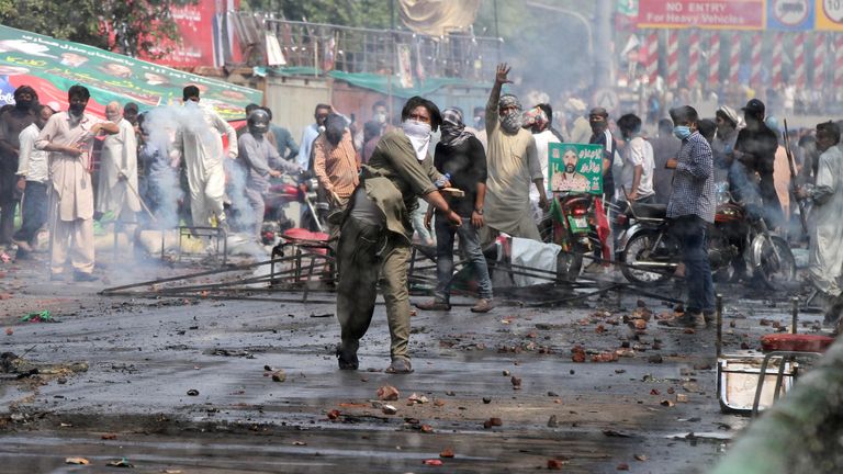 A supporter of former Pakistani Prime Minister Imran Khan throws stones at police during clashes in Lahore