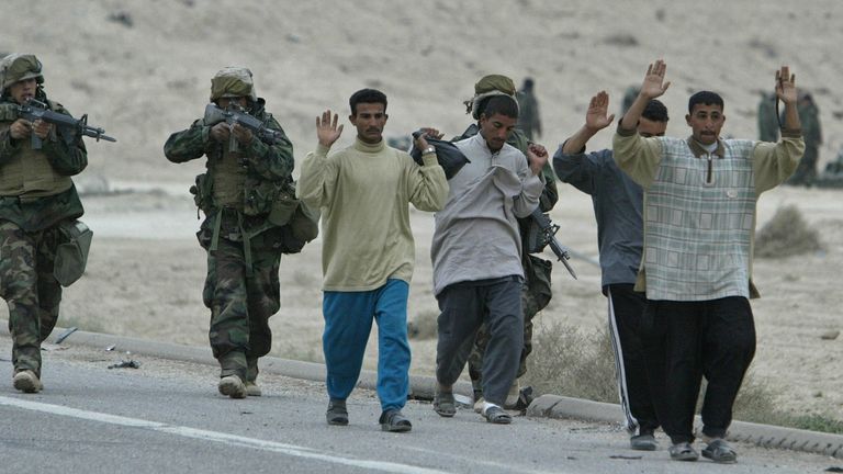 U.S. troops escort a group of Iraqi soldiers in civilian clothes north of Basra, Iraq, in 2003