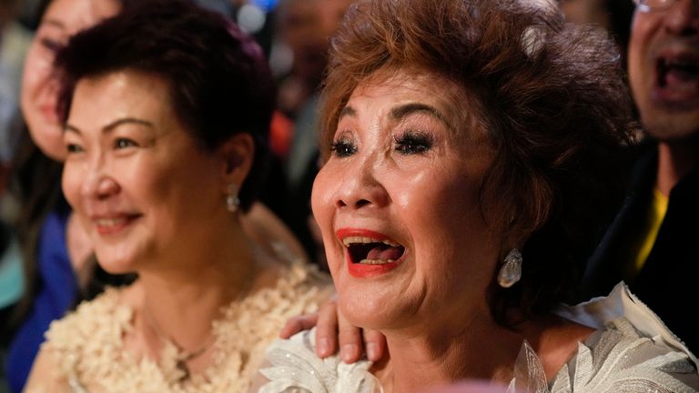 Janet Yeoh, right, mother of Michelle Yeoh, celebrates after her daughter won in the best actress category during the 95th Academy Awards in Los Angeles, as seen in a live view event at a cinema in Kuala Lumpur, Malaysia, Monday, March 13, 2023. (AP Photo/Vincent Thian)