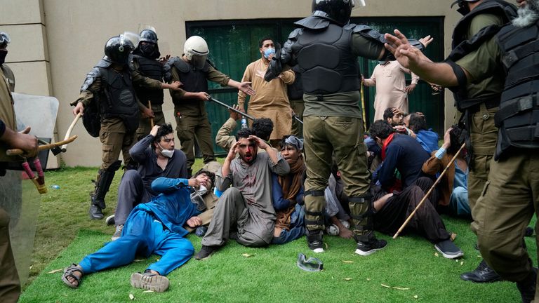 Police detain Mr Khan's supporters during a search operation of his home on Saturday