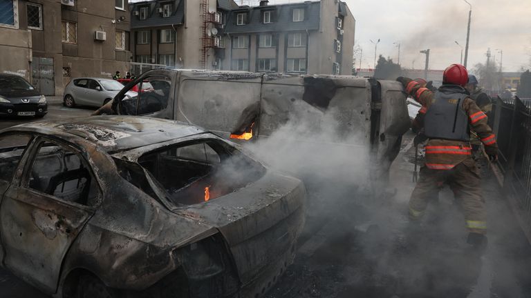 Emergency workers in Kyiv extinguish fire in vehicles at the site of a Russian missile strike