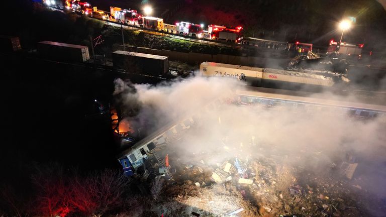 Smoke rises from trains as firefighters and rescuers operate after a collision near Larissa city, Greece, early Wednesday, March 1, 2023. The collision between a freight and passenger train occurred near Tempe, some 380 kilometers (235 miles) north of Athens, and resulted in the derailment of several train cars. (AP Photo/Vaggelis Kousioras)