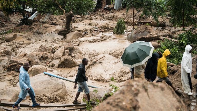 People cross a raging river in Blantyre, Malawi, Monday, March 13, 2023. An unrelenting Cyclone Freddy that is currently battering southern Africa has killed at least 56 people in Malawi and Mozambique since it struck the continent for a second time on Saturday night, authorities in both countries have confirmed. (AP Photo/Thoko Chikondi)