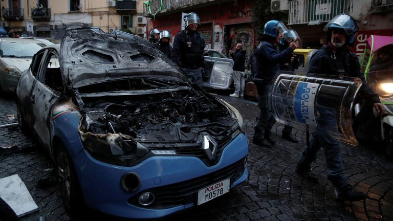 Police officers walk next to a police car which was burnt during clashes between Eintracht Frankfurt fans and Italian police ahead of a UEFA Champions League soccer match between Napoli and Eintracht Frankfurt in Naples, Italy, March 15, 2023. REUTERS/Stringer