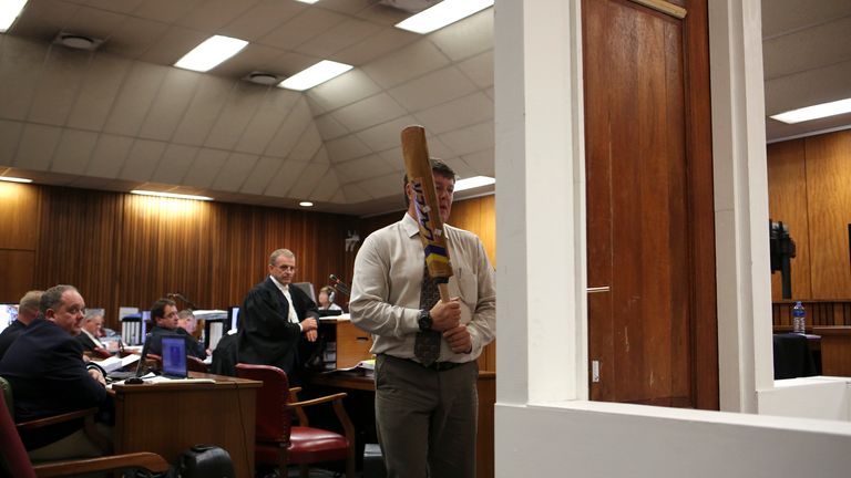 A policeman re-enacts the night of the murder with the cricket bat 