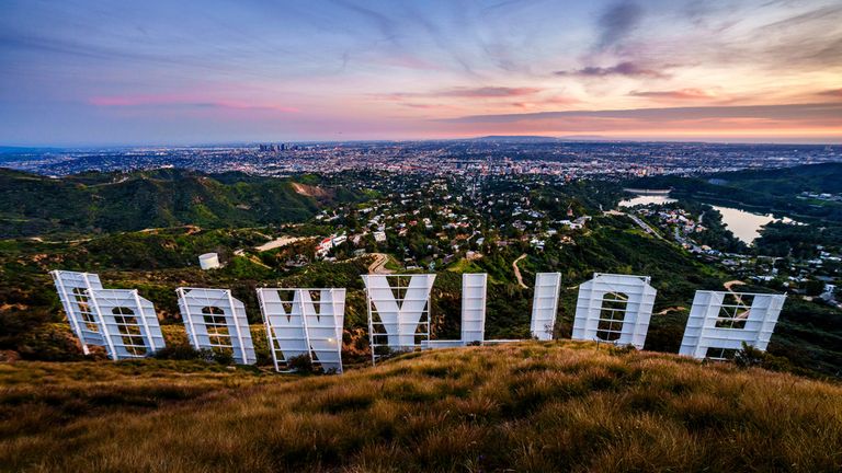 Sunset casts a pink glow over the Los Angeles skyline as seen from behind the famous Hollywood sign Wednesday evening, March 8, 2023. The 95th annual Academy Awards will be held Sunday at the Dolby Theatre in the Hollywood section of Los Angeles. (AP Photo/J. David Ake)