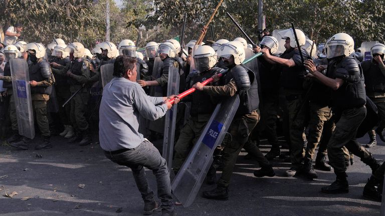 A supporter of former Prime Minister Imran Khan&#39;s party scuffles with riot police