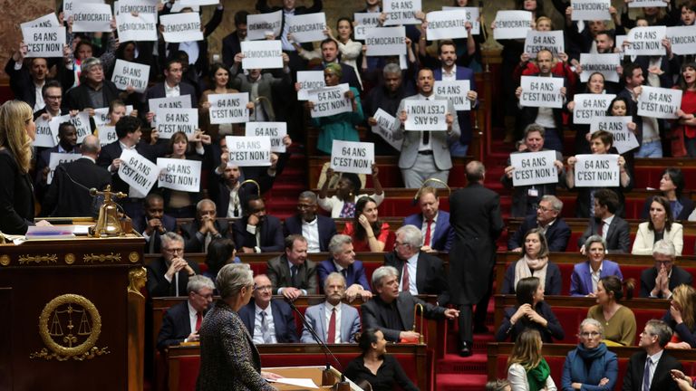 Fransa Başbakanı Elisabeth Borne, 16 Mart 2023'te Fransa'nın Paris kentindeki Ulusal Meclis'te emeklilik reformu yasa tasarısı hakkında bir konuşma yapmak üzere gelirken sol görüşlü milletvekilleri pankartlar tutuyor ve Fransız milli marşı Marsilya'yı söylüyor. REUTERS/Pascal Rossignol