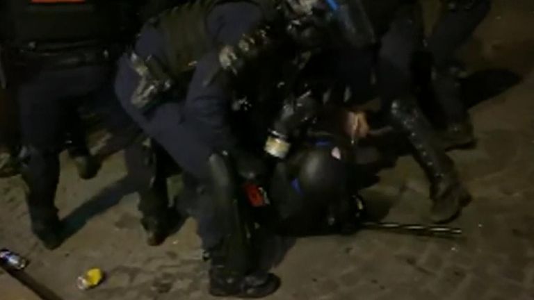 A police officer appears injured and is helped by colleagues during protests