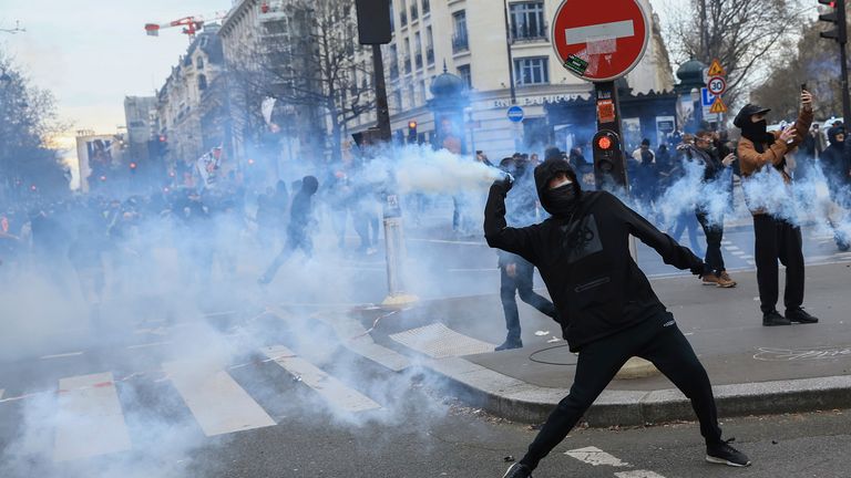 A protester throws a tear gas canister as he scuffles with riot police during a rally in Paris, Thursday, march 23, 2023. French unions are holding their first mass demonstrations Thursday since President Emmanuel Macron enflamed public anger by forcing a higher retirement age through parliament without a vote. (AP Photo/Aurelien Morissard)