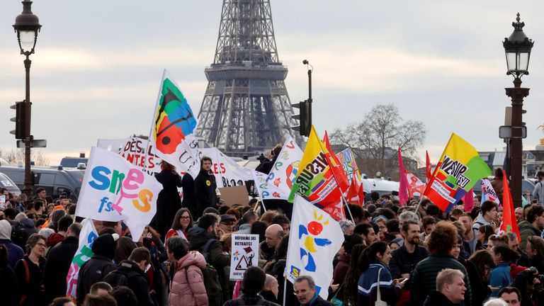 Göstericiler, Fransa Başbakanı Elisabeth Borne'nin özel bir madde olan 49.3 maddesinin kullanıldığını duyurmak için yaptığı konuşmanın ardından, arka planda Eyfel Kulesi ile Ulusal Meclis yakınlarındaki place de la Concorde'da toplanan pankartlarla protesto ediyor. Fransız Anayasası, emeklilik reformu yasa tasarısını milletvekillerinin oylaması olmadan parlamentonun alt kanadından geçirecek, 16 Mart 2023, Paris, Fransa. REUTERS/Pascal Rossignol