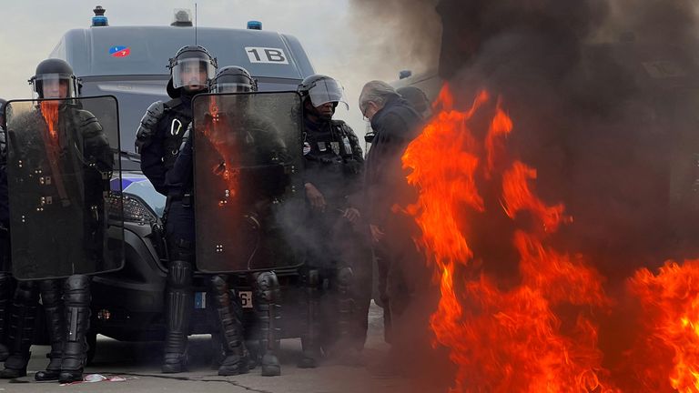 French gendarmes and CRS riot police stand on position near a fire as demonstrators gather on Place de la Concorde near the National Assembly to protest after French Prime Minister Elisabeth Borne delivered a speech to announce the use of the article 49.3, a special clause in the French Constitution, to push the pensions reform bill through the lower house of parliament without a vote by lawmakers, in Paris, France, March 16, 2023. REUTERS/Lucien Libert